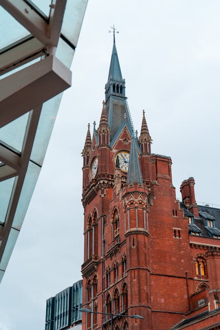 A busy urban scene outside a historic station entrance featuring a large, arched glass facade with a clock tower on top. In the foreground, a woman with light brown hair, wearing a beige jacket and li